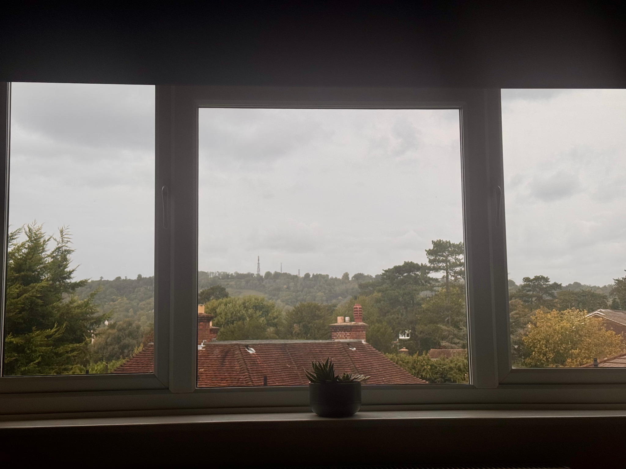 The bedroom window looking across rooftops and trees towards Reigate Hill